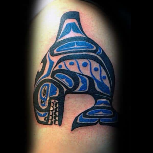 Tribal-inspired orca tattoo on the upper arm, featuring bold black and blue patterns, with intricate details forming the whale's shape in a striking and symbolic design.