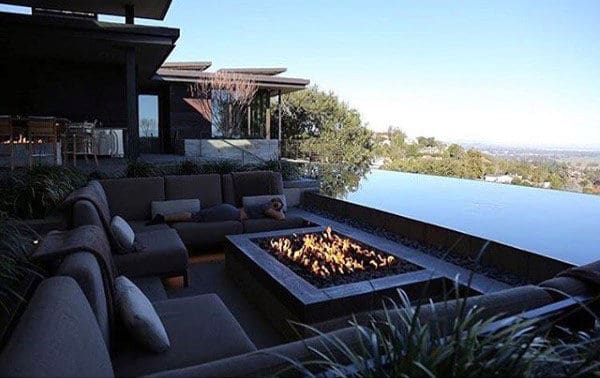 Outdoor seating area with a fire pit, near an infinity pool, and a scenic view of the landscape and sky