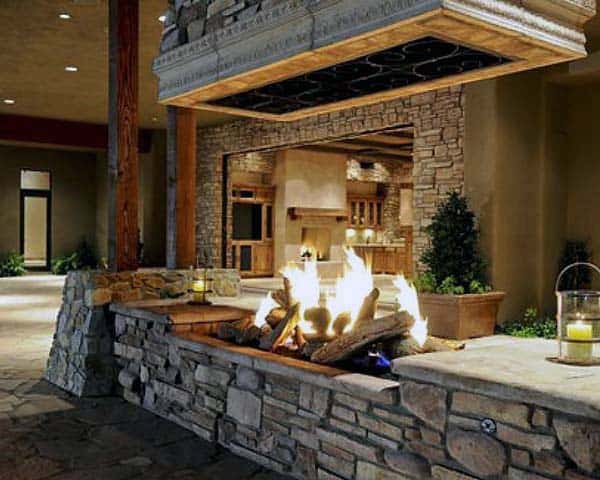 Cozy indoor-outdoor stone fireplace with lit candles and surrounding rustic decor