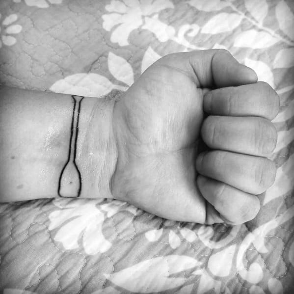 Minimalist paddle tattoo wrapped around the wrist, representing a passion for paddling, adventure, and a connection to water.