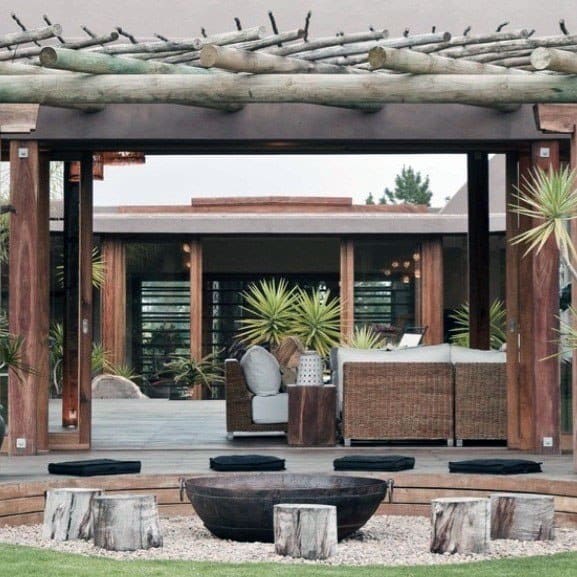 Nature-inspired pavilion with log accents, comfortable seating, and a firepit surrounded by tree stump stools.