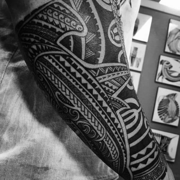 Close-up of a Polynesian tribal tattoo sleeve with bold geometric shapes and traditional motifs symbolizing ancestry and strength.