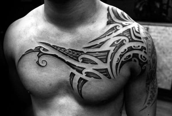 Cool Polynesian Tattoo On Mans Chest And Shoulder With Negative Space Tribal Design