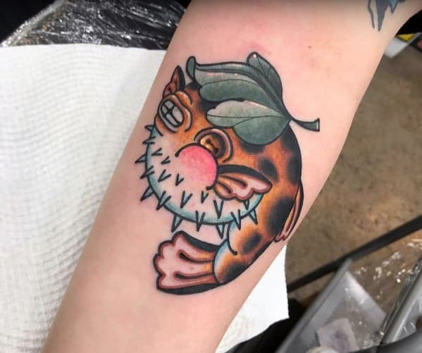 Traditional-style pufferfish tattoo with bold outlines, vibrant colors, and a leaf detail, giving it a playful and artistic appearance.