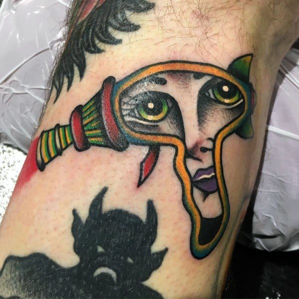 Creative ray gun tattoo with a surreal twist, featuring a woman's face integrated into the design with bold colors and traditional shading.