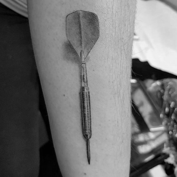 Realistic black and grey tattoo of a single dart with shadow detail, symbolizing focus, precision, and dedication to the game.
