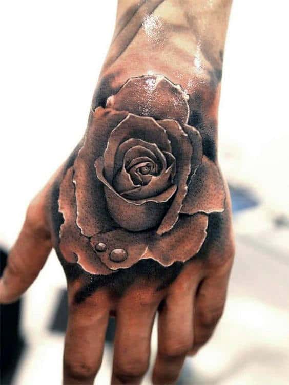 Tattoo of a detailed rose with water droplets on the back of a hand