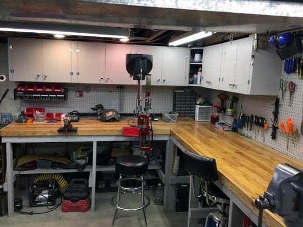 Spacious reloading room with wooden countertops, organized tools on pegboards, and ample storage cabinets