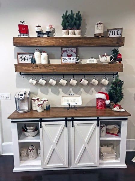 Rustic coffee bar with white cabinet, wooden shelves, festive mugs, and Christmas decor.