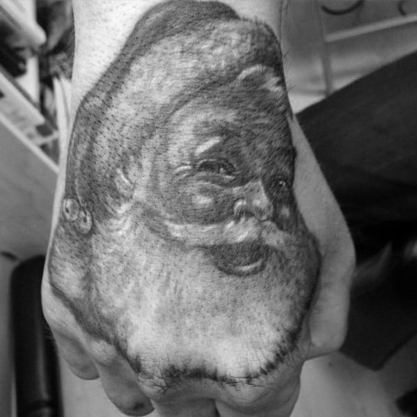Realistic black and grey Santa Claus tattoo on the hand, featuring fine shading and detailed facial expression for a classic holiday look.