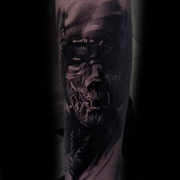 Dark and haunting scarecrow tattoo with a stitched face, hollow eyes, and shadowy details, rendered in deep black realism.