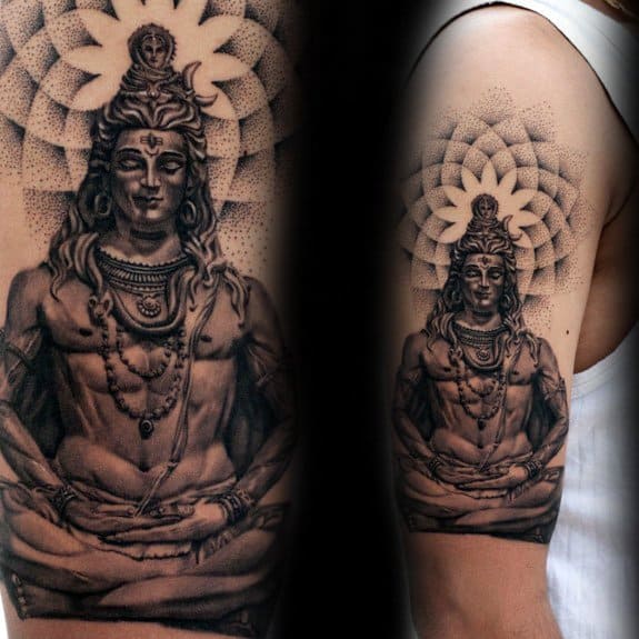 Upper arm tattoo of Lord Shiva in deep meditation, seated with serene power, framed by a large, detailed mandala radiating divine symmetry.