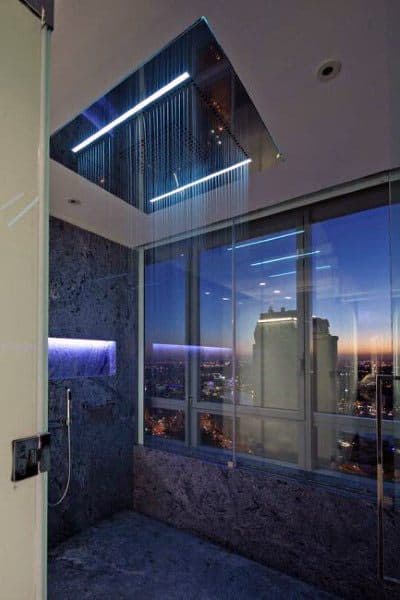 Luxurious shower with LED lighting and stunning sunset city view through expansive windows