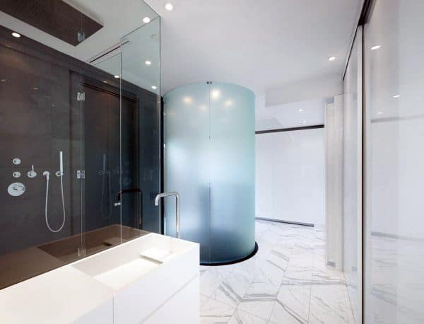 Modern bathroom featuring a sleek glass shower, cylindrical frosted enclosure, and pristine white marble flooring