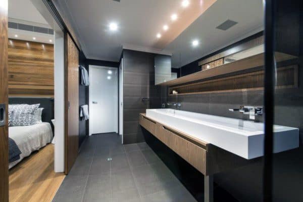 Modern bathroom with double sink, large mirror, and view into adjacent bedroom