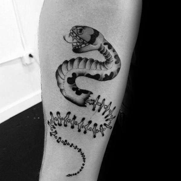 Snake skeleton tattoo on the upper arm, blending a detailed skull and bones with bold black ink patterns for a unique, artistic design.