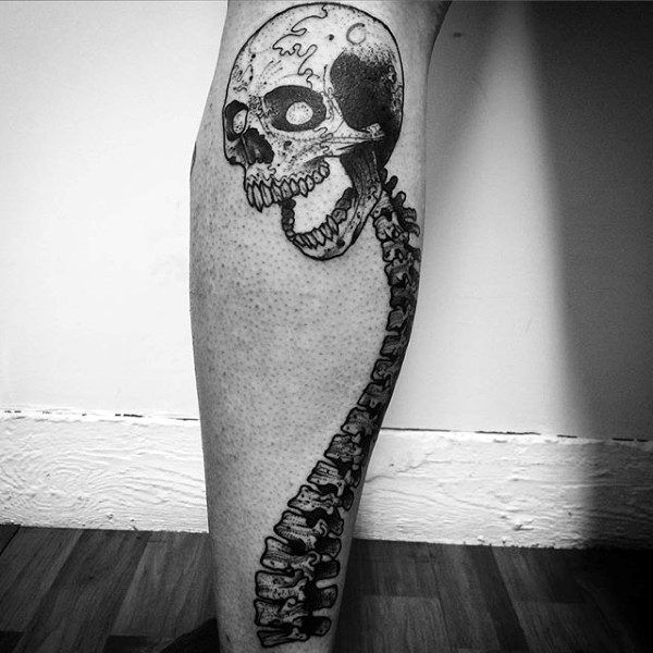 Tattoo of a skull and spine on a person's leg, in black and grey ink