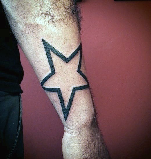 Tattoo of a black outlined star on a person's forearm