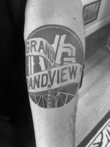 Bold black and grey tattoo of a circular street sign reading 'Grandview' with intricate details and a realistic, urban-style design.