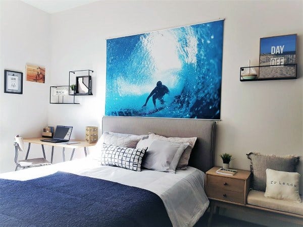 Modern bedroom with a surf-themed decor, featuring a surf photo above the bed, a desk, and a bedside table