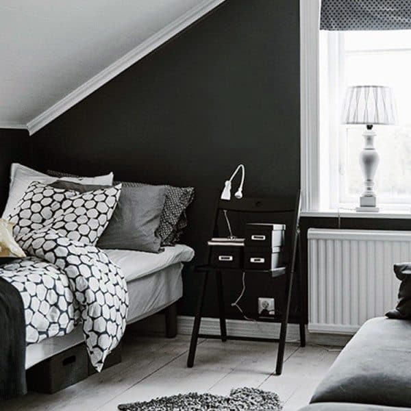 Cozy bedroom with a dark wall, bed with patterned pillows, side table, lamp, and window providing natural light