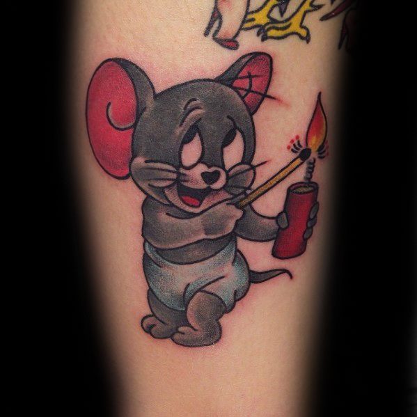 Colorful tattoo of baby Jerry in a diaper lighting a firecracker with a matchstick, inked on a man’s leg in cartoon style.