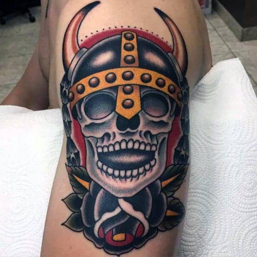 Tattoo of a horned skull in a helmet, surrounded by flowers on leg