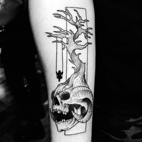 Forearm tattoo of a skull with tree branches and a swing hanging down