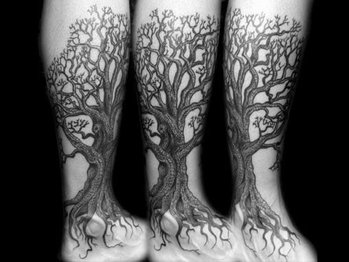 Intricate black ink tree tattoo wrapping around the leg, featuring detailed branches and roots extending onto the foot for a natural look.