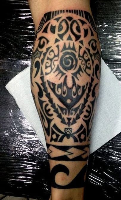 Leg tattoo featuring intricate black tribal patterns and geometric shapes