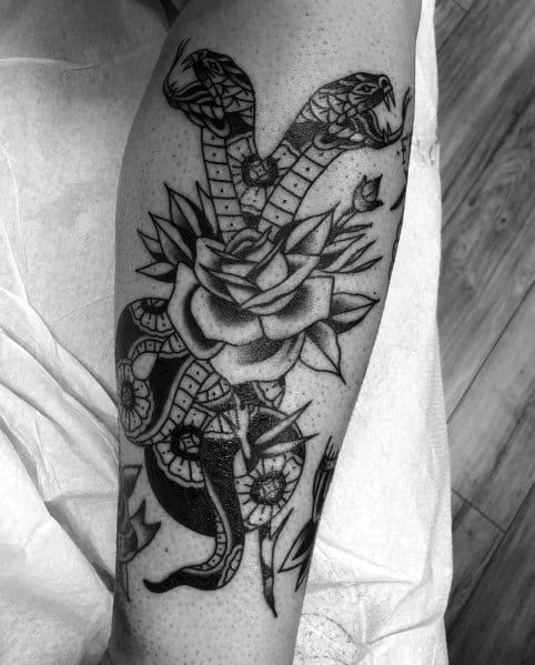 Black and grey two-headed snake tattoo intertwined with a detailed rose, placed on the leg for a bold and intricate design.