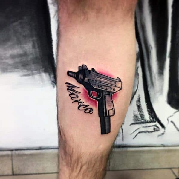 Black Uzi tattoo on a man's leg with red shading and 'Marco' in cursive. Bold design with a striking color contrast.