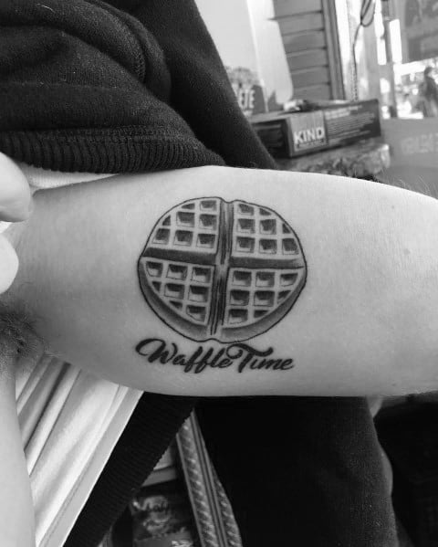 Minimalist waffle tattoo with bold shading and the phrase "Waffle Time" in cursive, creating a simple yet striking breakfast-inspired design.