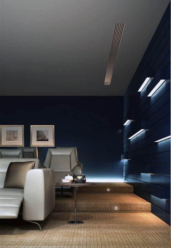 Modern living room with blue accent wall, light gray sofas, home theater setup, decorative lighting, and framed artwork