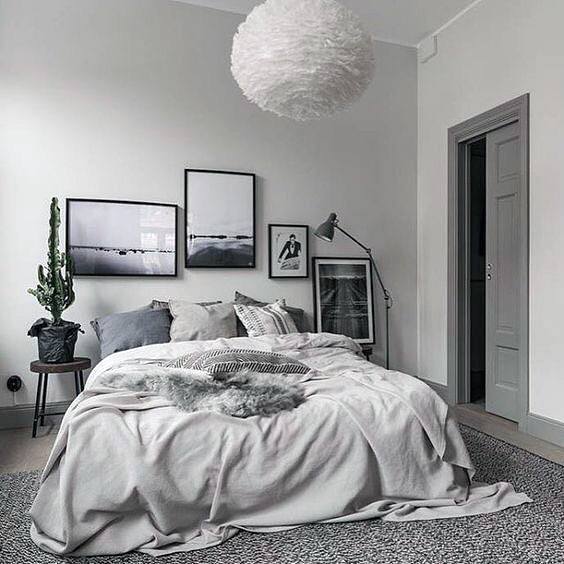 Cozy bedroom with a fluffy pendant light, framed artwork, cactus, and a grey-toned bed with layered bedding