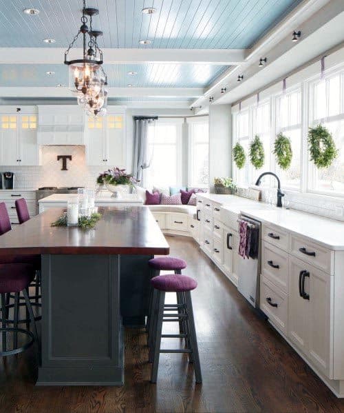 White kitchen with blue ceiling, wood island, and purple bar stools.