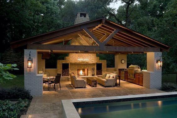 Spacious poolside pavilion with a stone fireplace, outdoor kitchen, and cozy seating area for relaxing evenings.