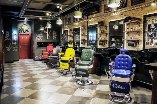 Barbershop with colorful vintage chairs, industrial lighting, and creative chalkboard-style decor.