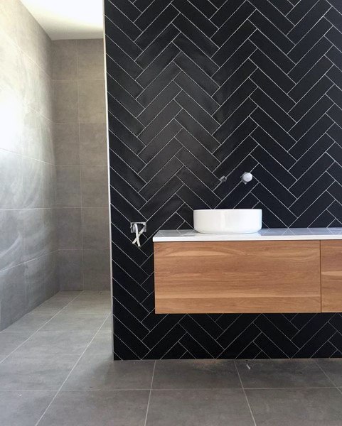 Modern bathroom with a black herringbone tile wall, floating vanity, and vessel sink