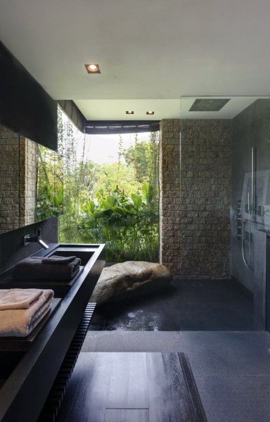 luxury contemporary bathroom stone walls walk-in shower black vanity forest view