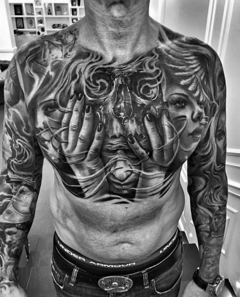 Surreal black and grey chest tattoo featuring female faces, hands, and flowing smoke, symbolizing emotion, duality, and inner turmoil.