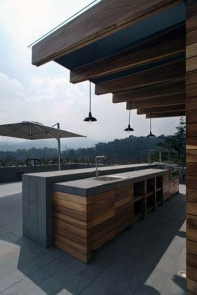 Modern outdoor bar with a wood pallet design, concrete countertops, and minimalist pendant lights.