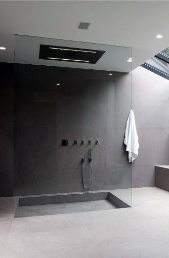 Sleek shower with glass enclosure, dark tiles, a rainfall showerhead, and a towel hanging on the wall