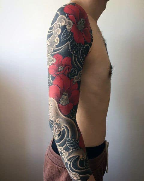Full sleeve Japanese-style tattoo with bold red flowers, flowing waves, and soft clouds, symbolizing beauty, strength, and harmony.