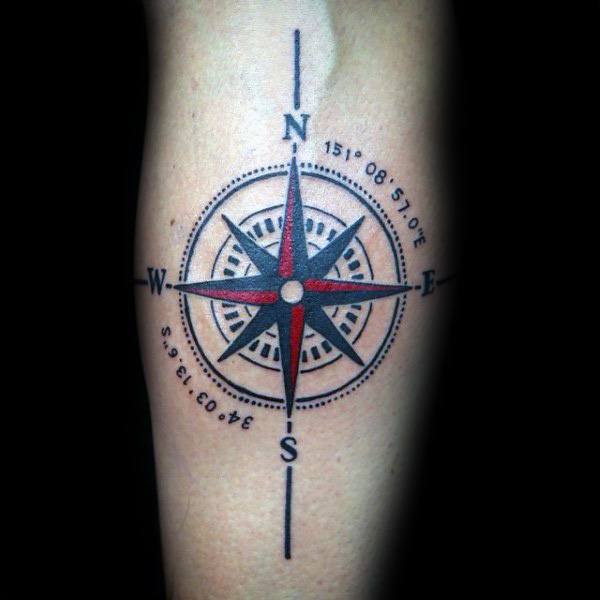 Bold compass tattoo with red and black details, featuring geographic coordinates, symbolizing direction, adventure, and personal journeys.