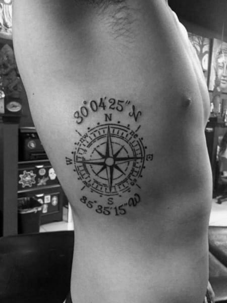 Compass coordinate tattoo on the ribcage with intricate detailing, symbolizing direction, adventure, and a meaningful location.