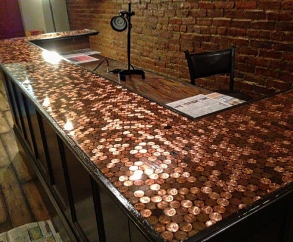 Bar top made from copper pennies with epoxy finish and brick wall backdrop.