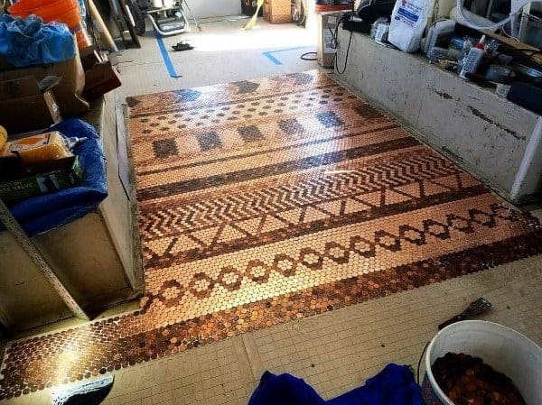 Penny tile floor with geometric patterns in copper tones, under construction in a workshop space.