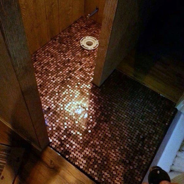 Room with copper penny tile flooring and wood-paneled walls under renovation.