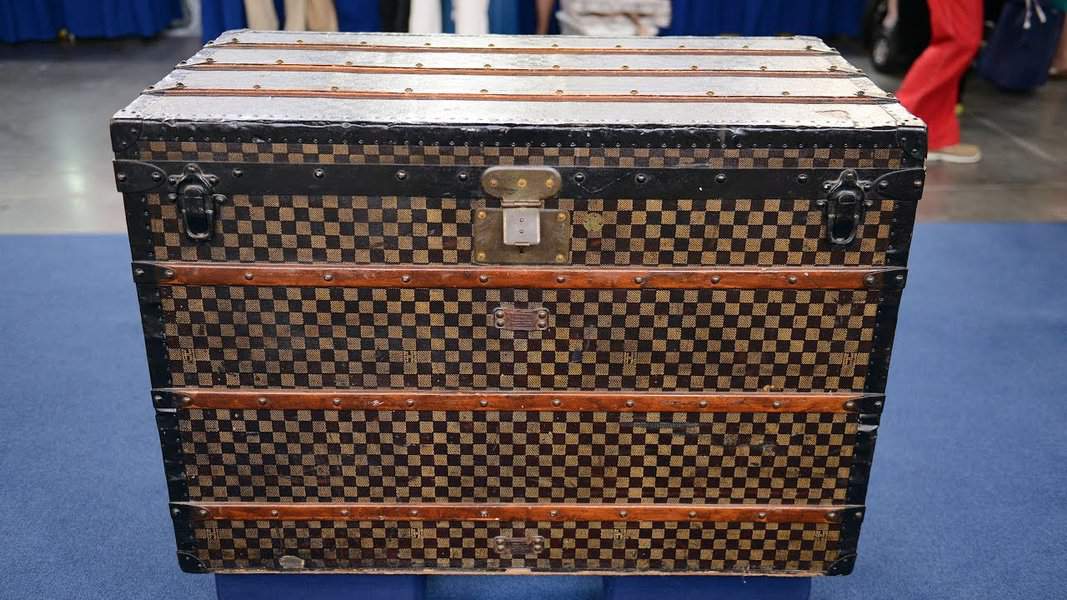 Vintage Louis Vuitton checkered trunk with metal accents and wooden reinforcements.